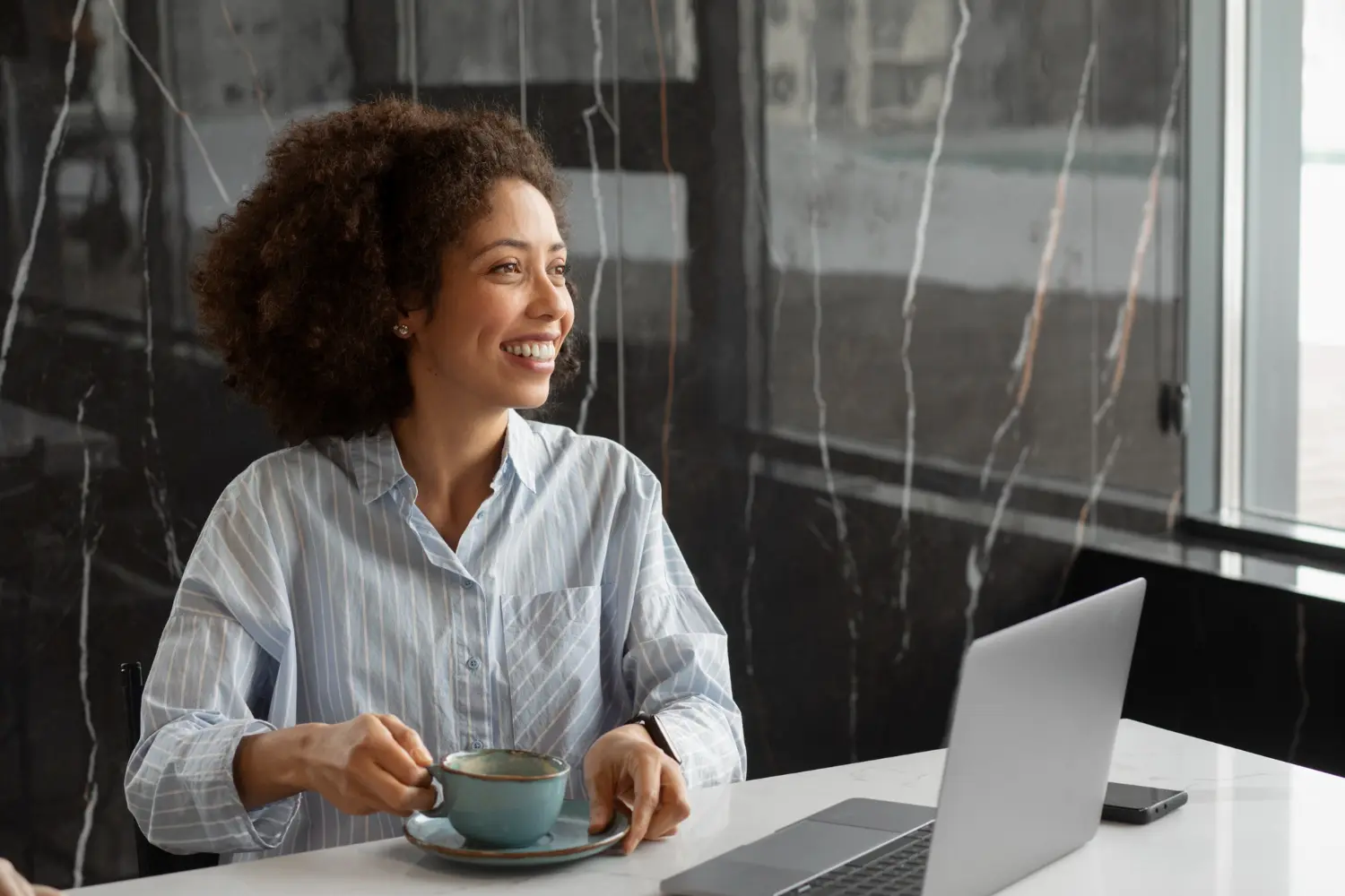 Trabalhadora sorrindo em ambiente moderno com notebook